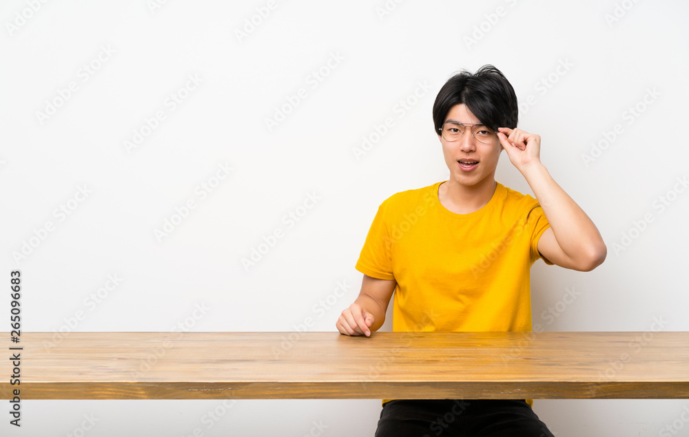 Asian man with yellow shirt with glasses and surprised Asian man with yellow shirt with glasses and surprised