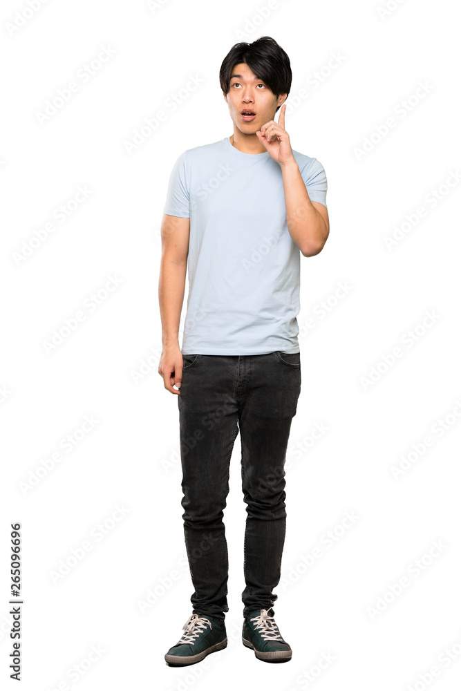 A full-length shot of a Asian man with blue shirt thinking an idea pointing the finger up over isolated white background A full-length shot of a Asian man with blue shirt thinking an idea pointing the finger up over isolated white background