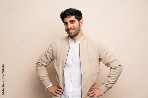 Young man over isolated wall posing with arms at hip and smiling