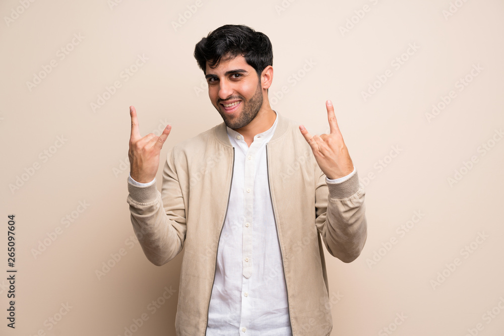 Young man over isolated wall making rock gesture Young man over isolated wall making rock gesture