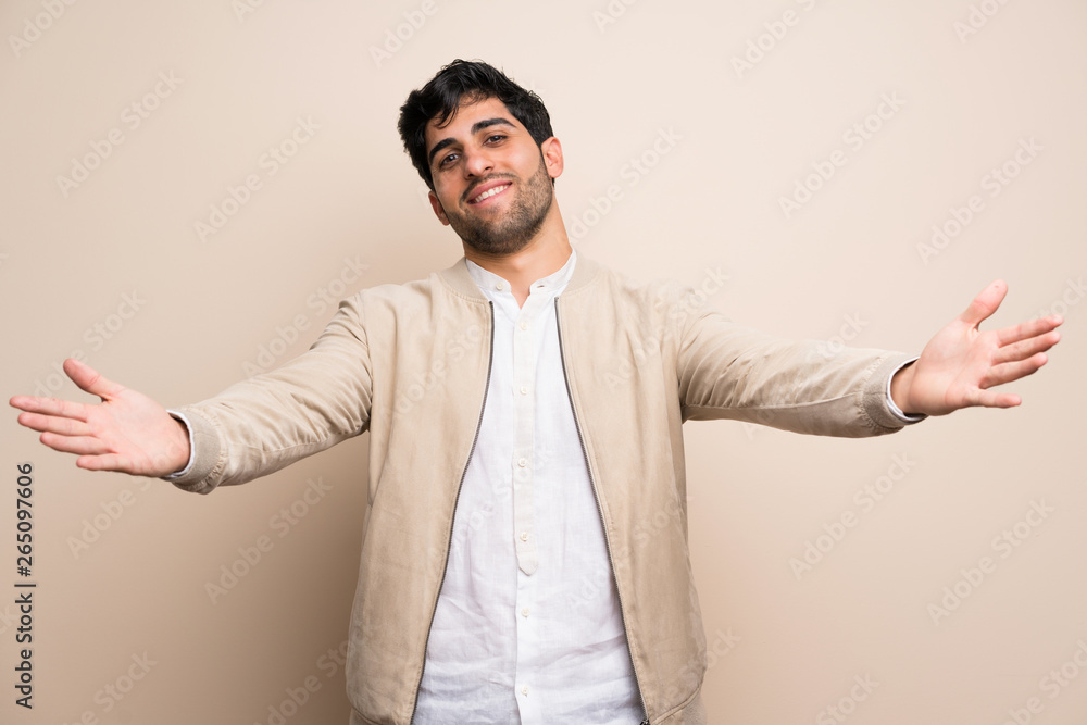 Young man over isolated wall presenting and inviting to come with hand