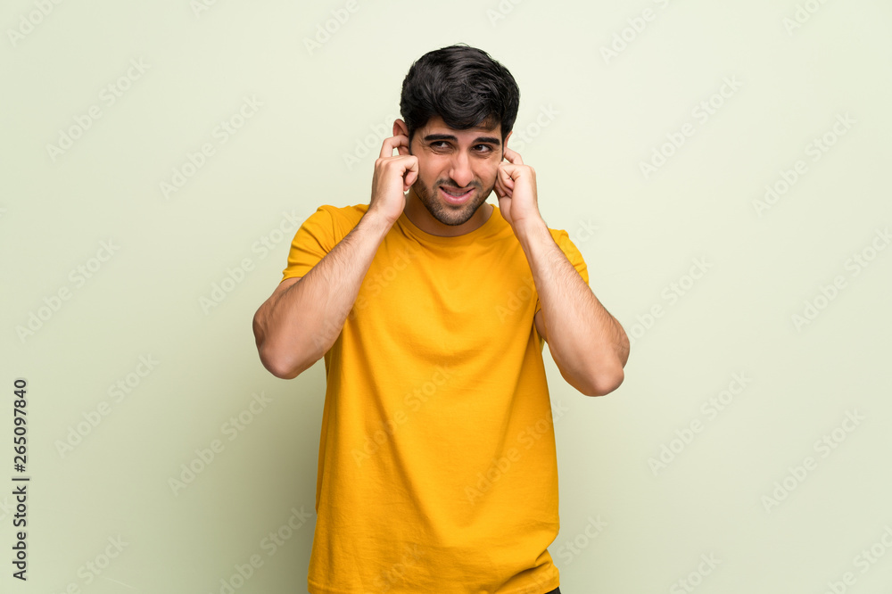 Young man over pink wall covering ears with hands. Frustrated expression Young man over pink wall covering ears with hands. Frustrated expression