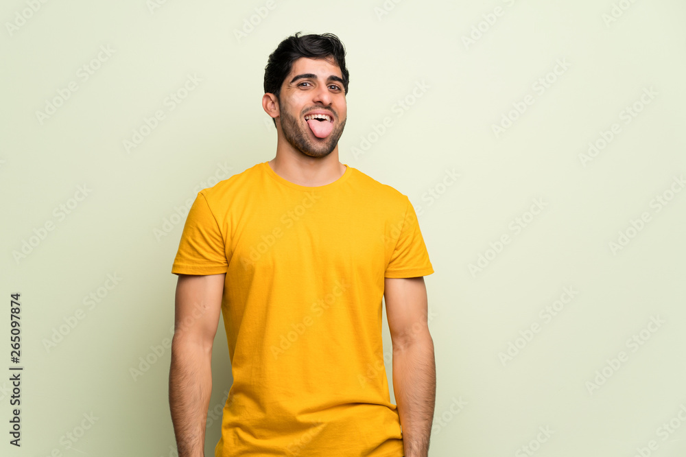 Young man over pink wall showing tongue at the camera having funny look Young man over pink wall showing tongue at the camera having funny look