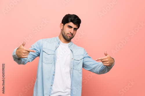 Young man over pink wall proud and self-satisfied