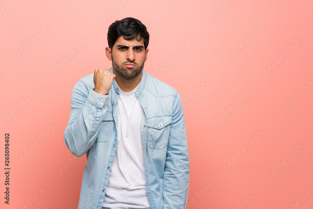 Fototapeta premium Young man over pink wall with angry gesture