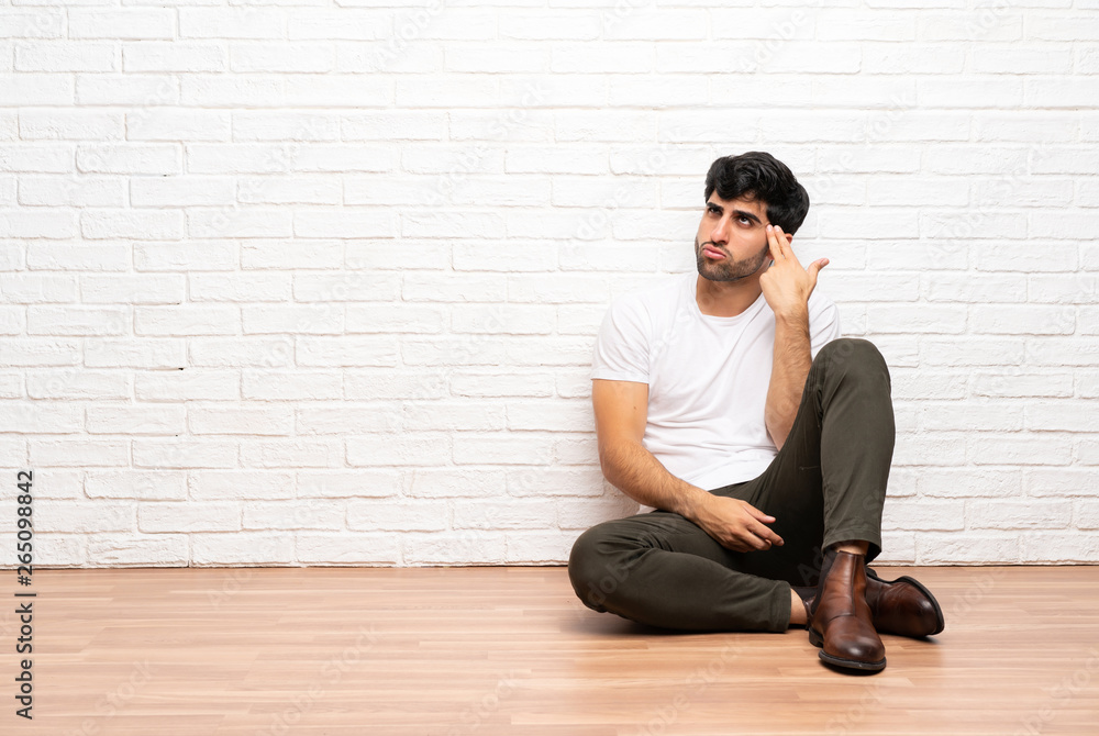 Young man sitting on the floor with problems making suicide gesture Young man sitting on the floor with problems making suicide gesture