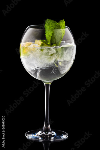 Big round wine glass with fresh cold lemonade isolated on black background