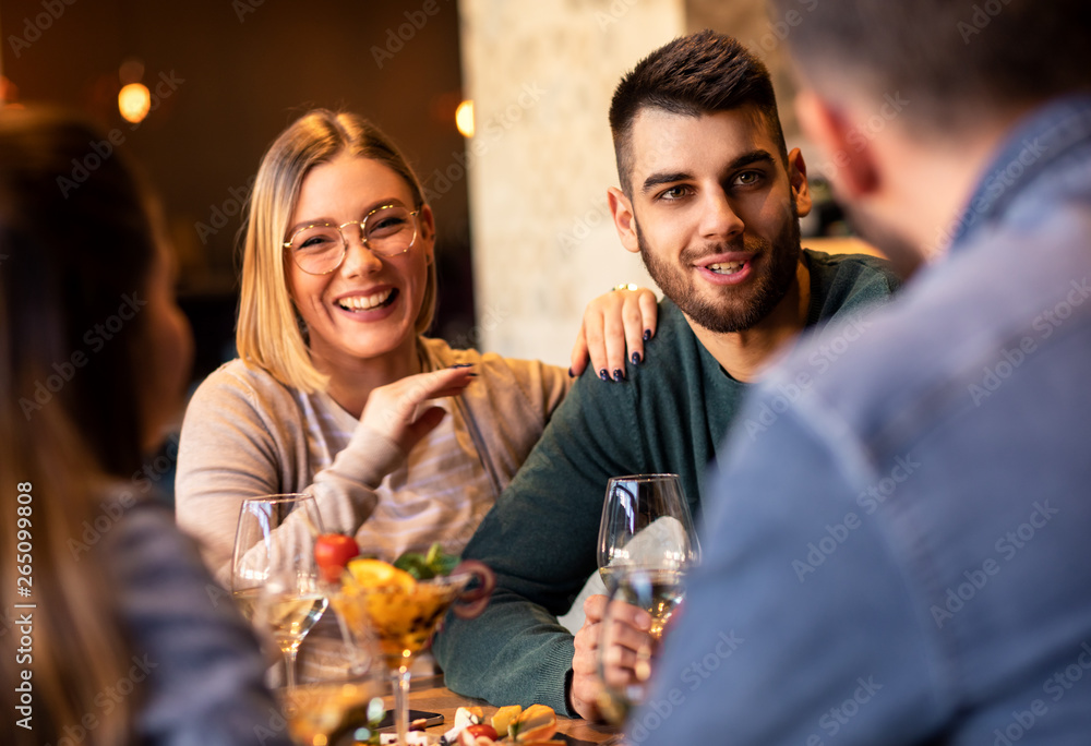 Group of young friends having fun in restaurant, talking and laughing while dining at table. Group of young friends having fun in restaurant, talking and laughing while dining at table.