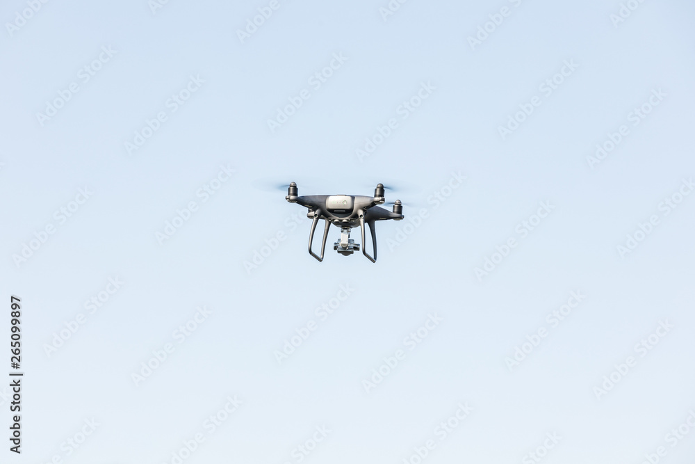 Landing a droned hand with spinning propellers. Flying drone on blue sky. Landing a droned hand with spinning propellers. Flying drone on blue sky.