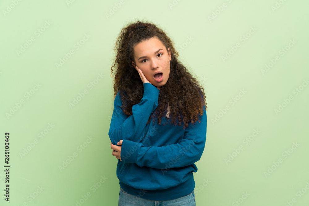 Teenager girl over green wall surprised and shocked while looking right Teenager girl over green wall surprised and shocked while looking right