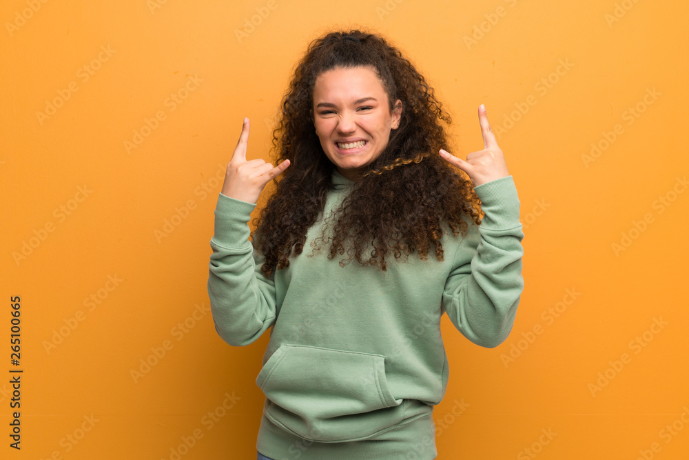 Teenager girl over ocher wall making rock gesture
