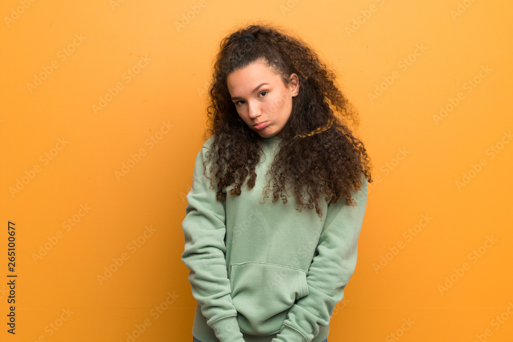 Teenager girl over ocher wall with sad and depressed expression Teenager girl over ocher wall with sad and depressed expression