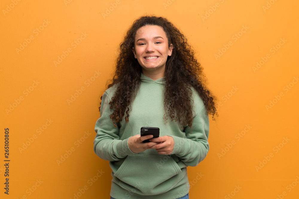 Teenager girl over ocher wall sending a message with the mobile Teenager girl over ocher wall sending a message with the mobile