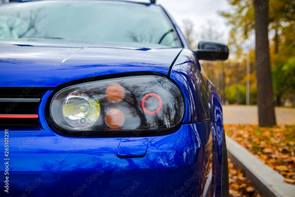Obraz premium Modified xenon headlights of blue modern car. Parked on the street