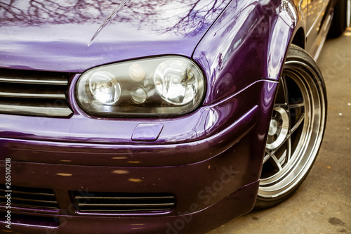 Modified headlights of tuned purple candy colored lowrider. Stance custom car with a forged polished wheels stays on a street © Dmitry Dven