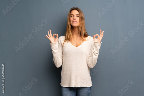 Blonde woman over grey background in zen pose