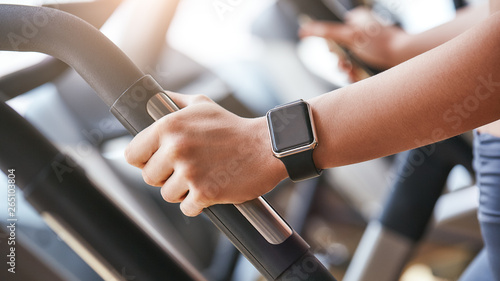Smart technologies. Close-up photo of smart watch on woman hand holding the handle of cardio machine in gym © Friends Stock