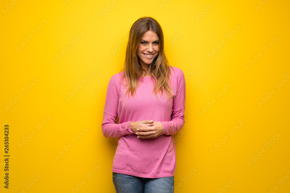 Obraz premium Woman with pink sweater over yellow wall laughing looking to the front