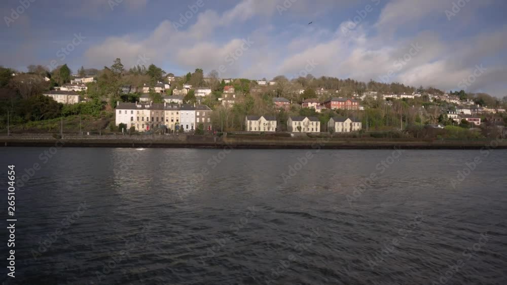 Pan shot of river and landscape in an urban setting with houses, with cars passing by in the background on a sunny day in Ireland. Pan shot of river and landscape in an urban setting with houses, with cars passing by in the background on a sunny day in Ireland.