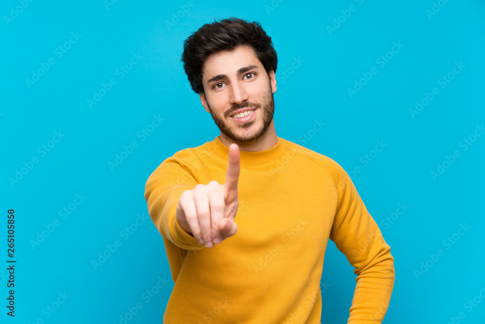 Handsome over isolated blue wall showing and lifting a finger Handsome over isolated blue wall showing and lifting a finger