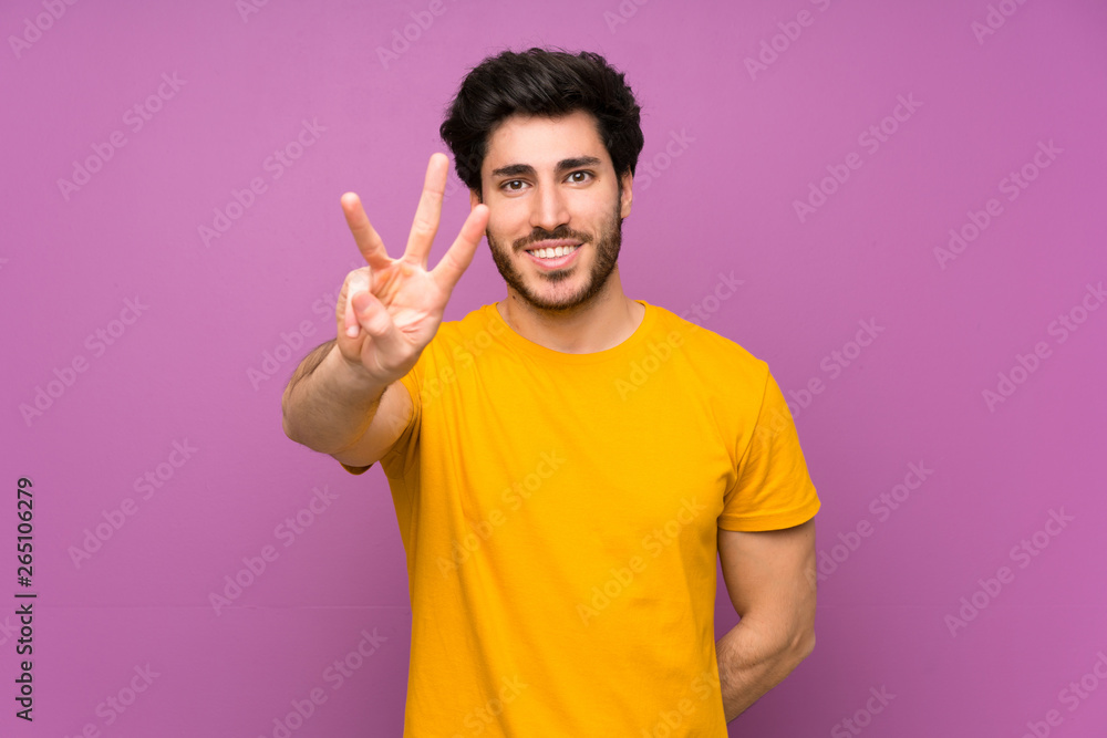 Handsome over isolated purple wall happy and counting three with fingers Handsome over isolated purple wall happy and counting three with fingers