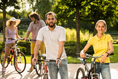 Young students with bicycles outdoors. Smiling tourists with bicycles at summer park. People, tourism and active lifestyle.