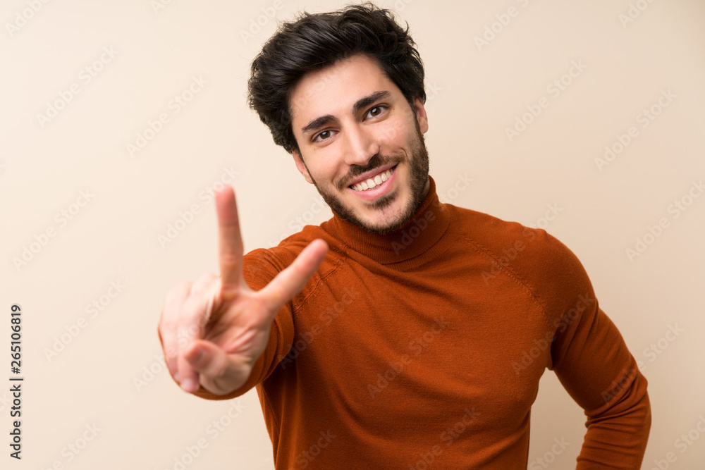 Handsome over isolated wall smiling and showing victory sign Handsome over isolated wall smiling and showing victory sign