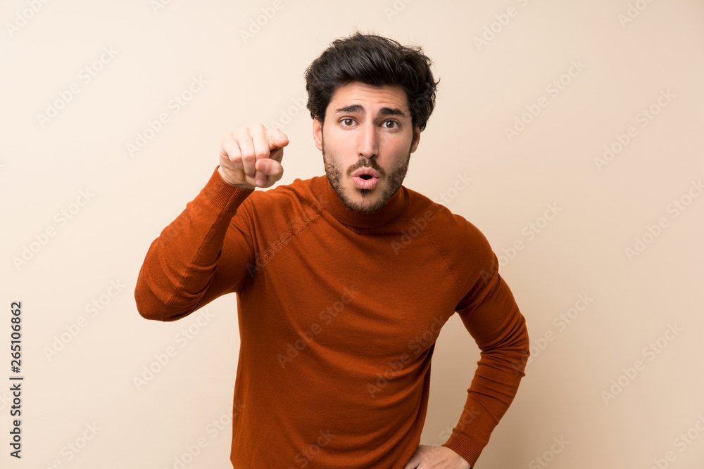 Handsome over isolated wall surprised and pointing front Handsome over isolated wall surprised and pointing front