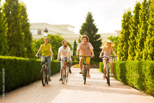 Happy young bike riders in summer park. Group of positive young people cycling outdoors. Summer travel concept.