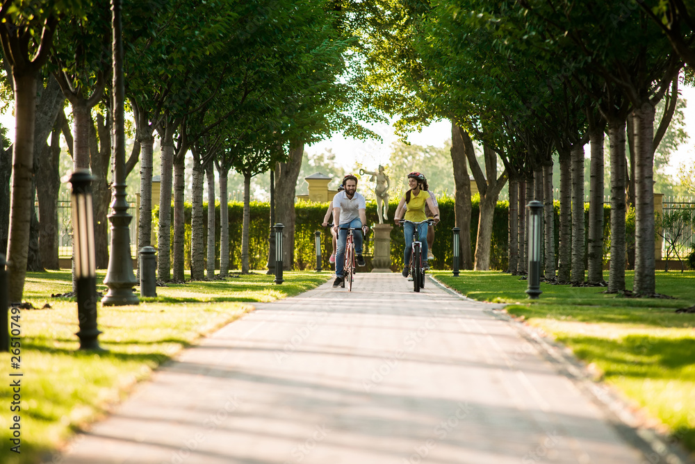 Fototapeta premium Young people cycling on road in park. Tourists on summer vacation. People and summer rest.