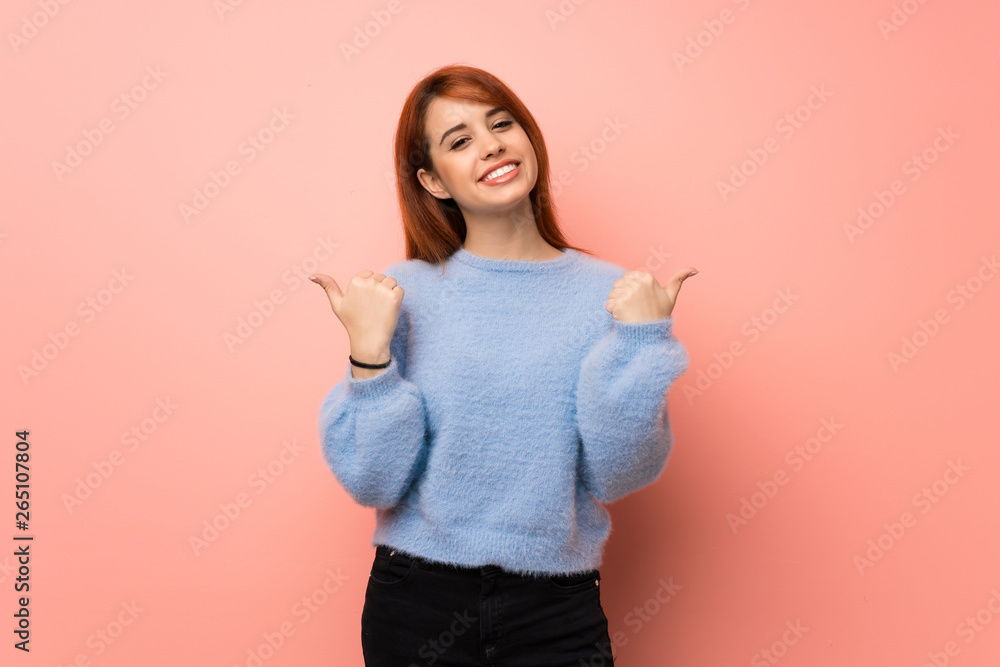 Young redhead woman over pink background giving a thumbs up gesture with both hands and smiling Young redhead woman over pink background giving a thumbs up gesture with both hands and smiling