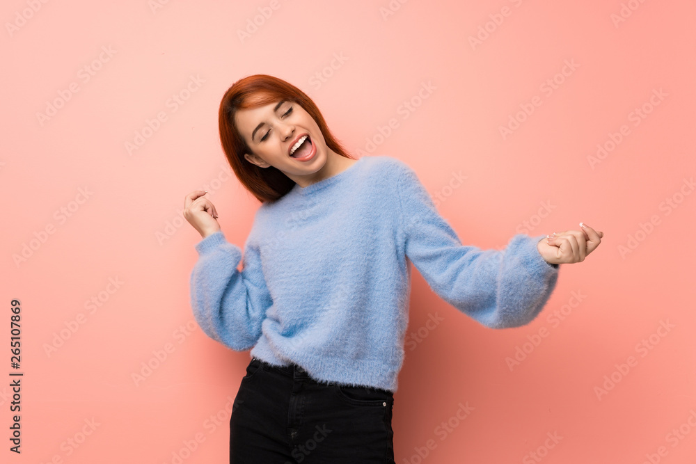 Young redhead woman over pink background enjoy dancing while listening to music at a party Young redhead woman over pink background enjoy dancing while listening to music at a party