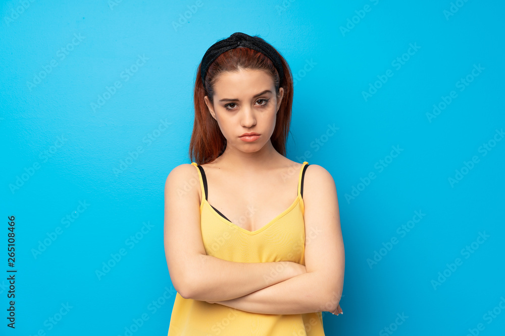 Young redhead woman over blue background feeling upset Young redhead woman over blue background feeling upset