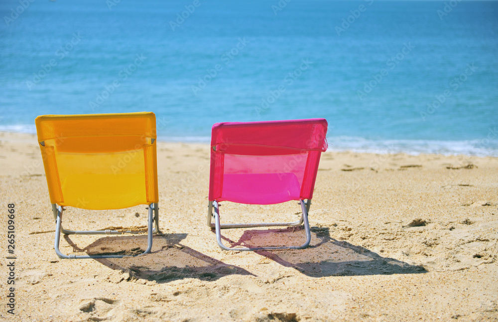 Two colorful beach chairs with blue sea water Two colorful beach chairs with blue sea water