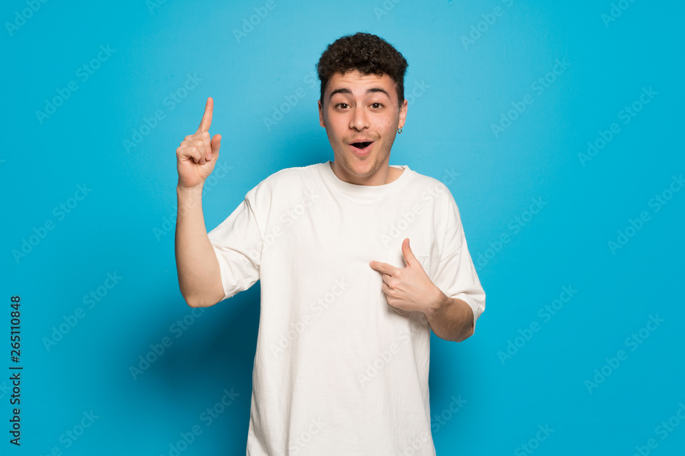 Young man over blue background with surprise and shocked facial expression Young man over blue background with surprise and shocked facial expression