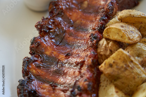 Close-up of grilled pork ribs with baked potatoes.