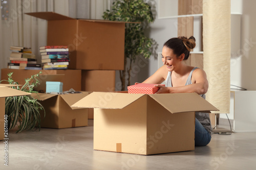 Happy woman moving home unboxing belongings in the night