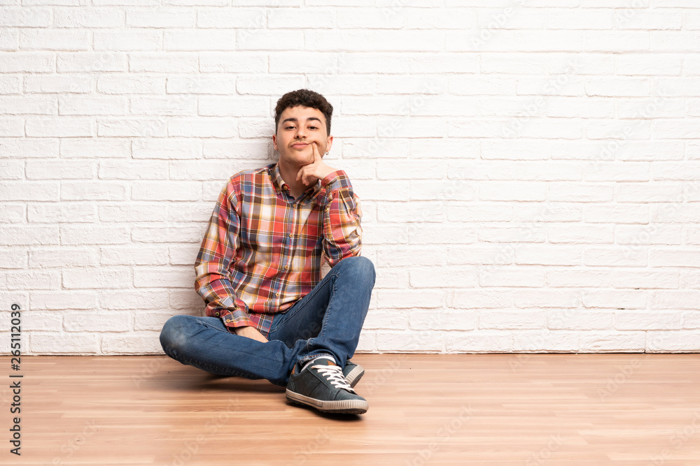 Young man sitting on the floor Looking front Young man sitting on the floor Looking front