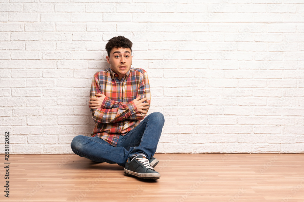Young man sitting on the floor freezing Young man sitting on the floor freezing