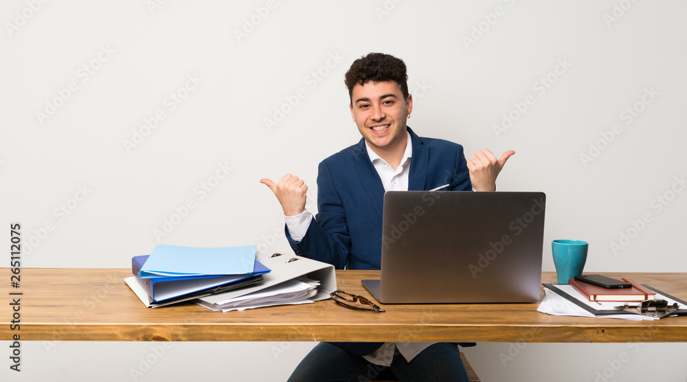 Business man in a office with thumbs up gesture and smiling Business man in a office with thumbs up gesture and smiling