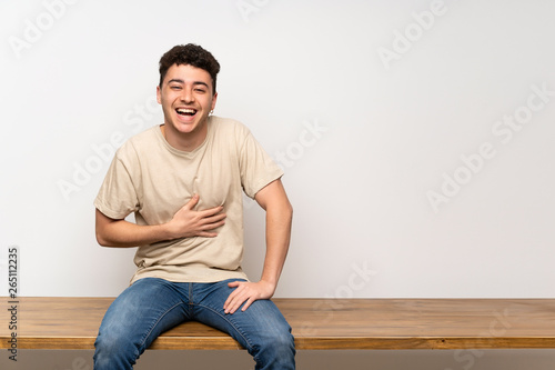 Young man sitting on table smiling a lot