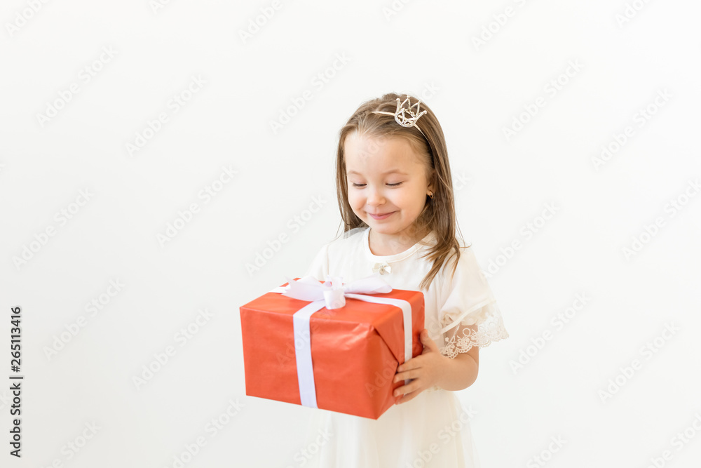 Childhood, children and holiday concept - little girl in white dress with gift box on white background Childhood, children and holiday concept - little girl in white dress with gift box on white background
