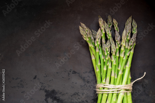 Fresh green asparagus against dark rustic background with plenty of copy space for your text. Overhead view, flat lay