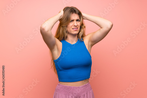 Young blonde woman over isolated pink background frustrated and takes hands on head