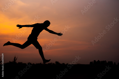 Fototapeta Naklejka Na Ścianę i Meble -  Man running alone at beautiful sunset in the road at park . Summer sport and freedom concept. Athlete training on dusk. - Image