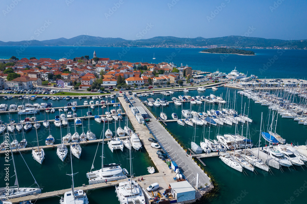 Aerial View of Yacht Club and Marina in Biograd na Moru. Summer time in Dalmatia region of Croatia. Coastline and turquoise water and blue sky. Photo made by drone from above.