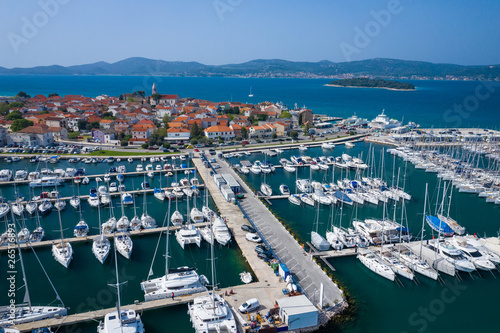 Aerial View of Yacht Club and Marina in Biograd na Moru. Summer time in Dalmatia region of Croatia. Coastline and turquoise water and blue sky. Photo made by drone from above. © Curioso.Photography