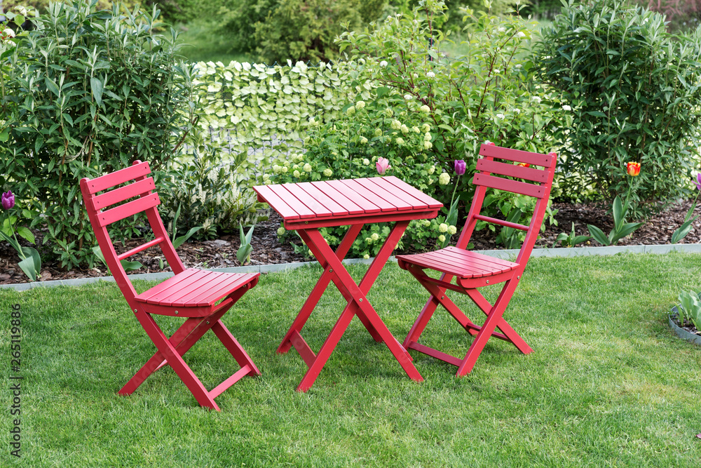 Relaxing area with two red chairs and red table in cozy garden Relaxing area with two red chairs and red table in cozy garden