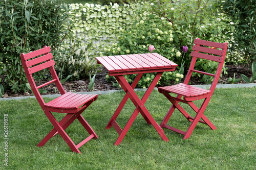 Relaxing area with two red chairs and red table in cozy garden