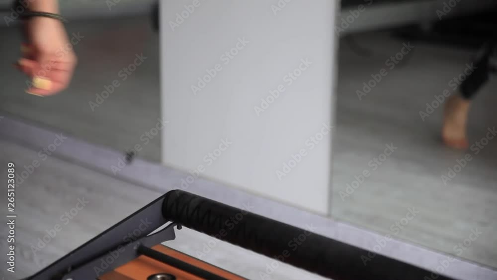 A woman's hand arranging reformer pilates foot bar. A woman's hand arranging reformer pilates foot bar.